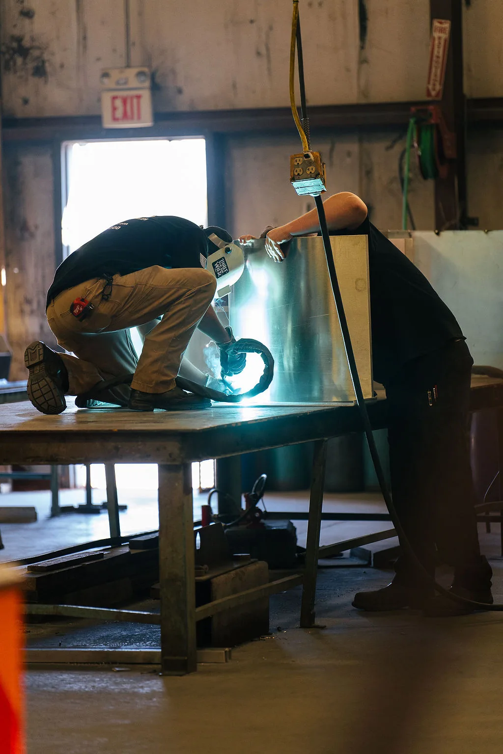 FES fabricator welding an aluminum compartment enclosure on a work table