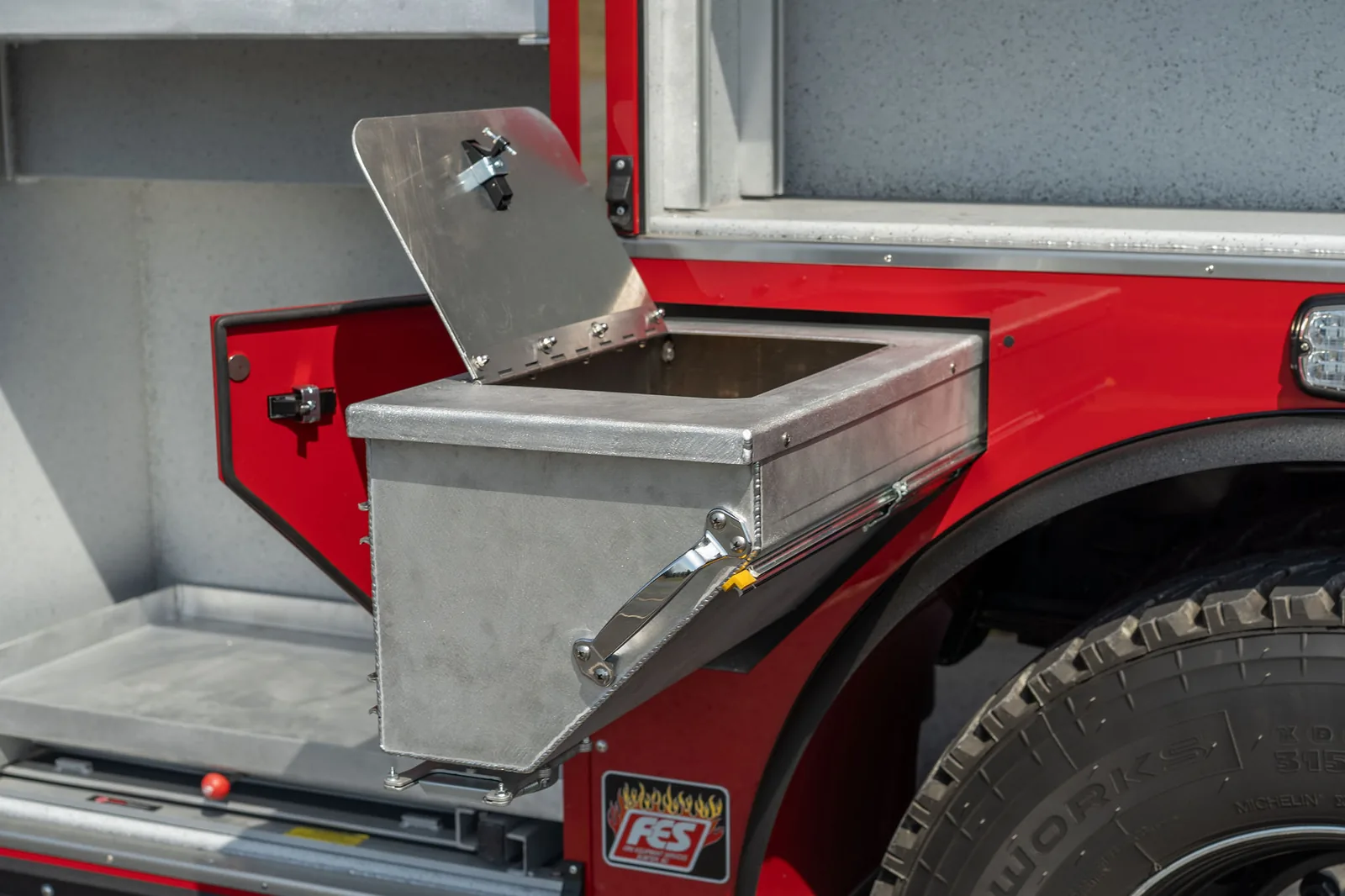 Fabricated aluminum wheel well compartment with lid open on an FES apparatus body