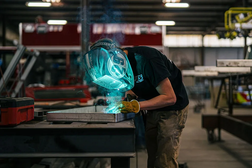 FES welder working a seam on an aluminum panel at a fabrication table