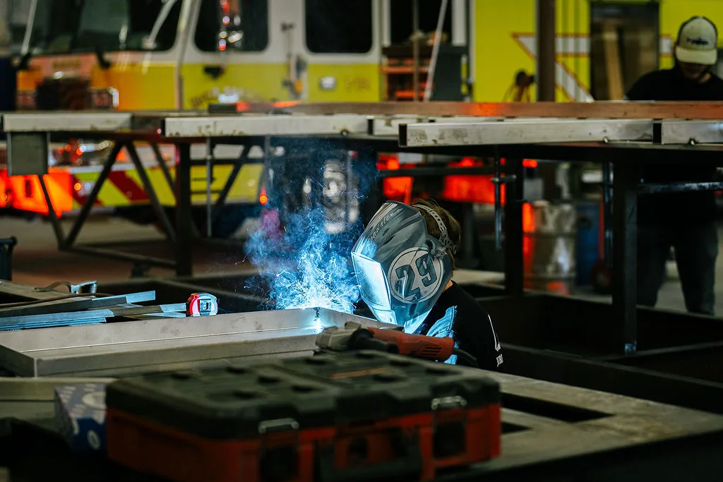 FES welder joining aluminum beneath a fixture table with a fire apparatus in the background